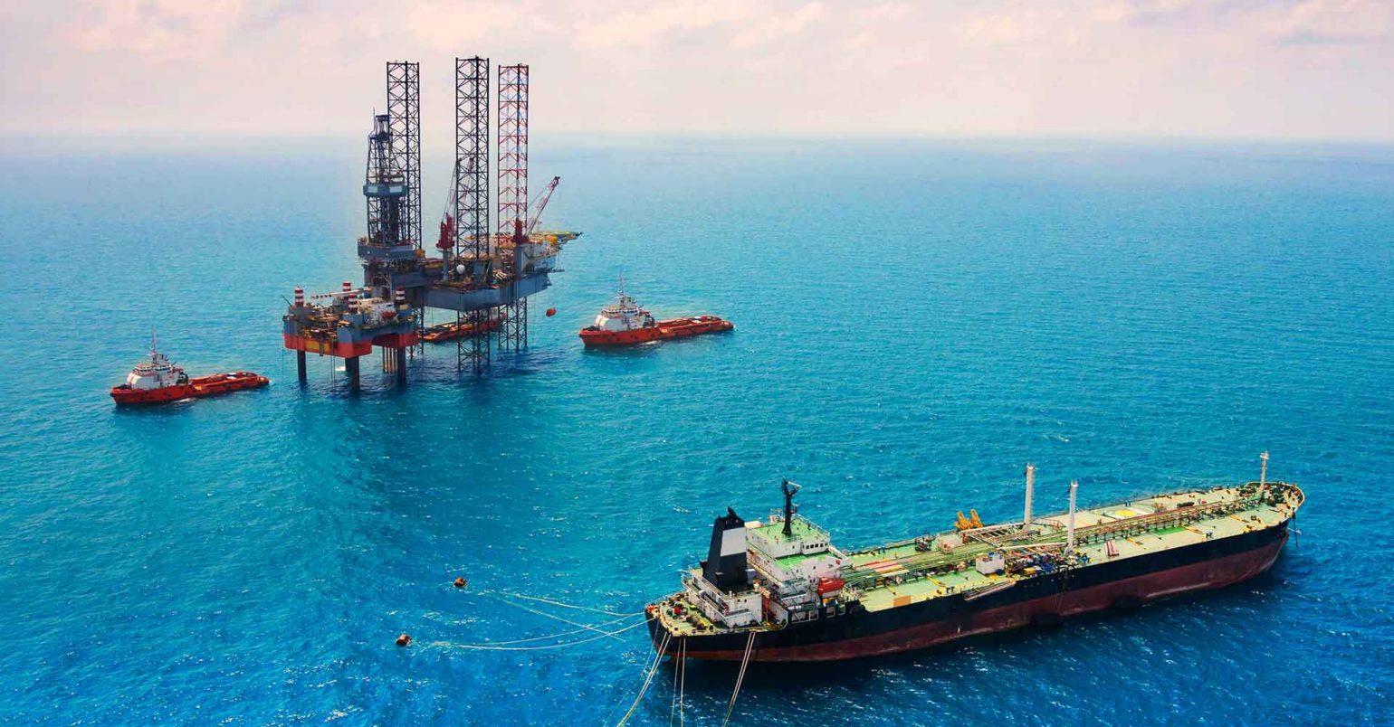 Photo of an oil tanker and oil rig at sea.