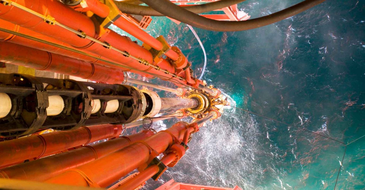 Closeup photo from oil rig with pipes extending down into the sea.